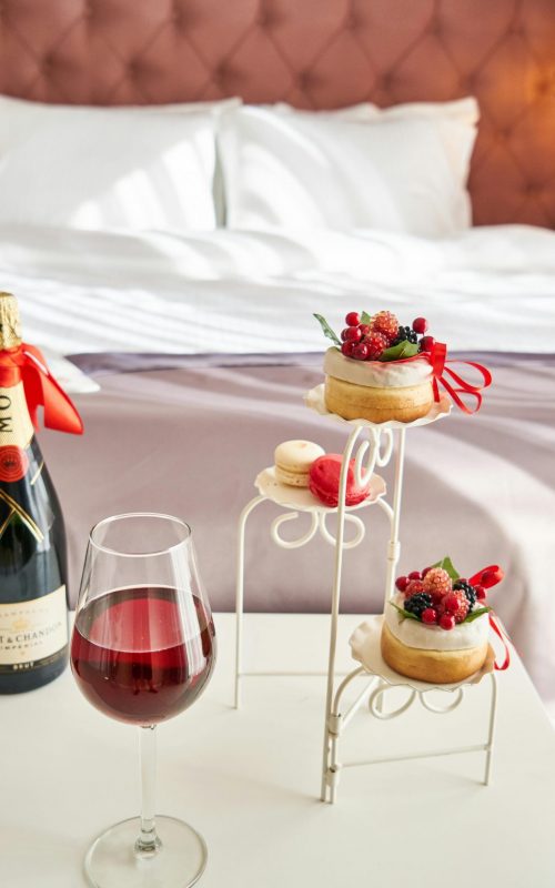 Elegant bedroom setting with champagne, wine glass, and desserts, creating a cozy ambiance.